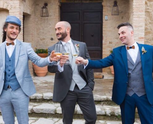 Tre ragazzi vestiti da invitati che brindano a un matrimonio