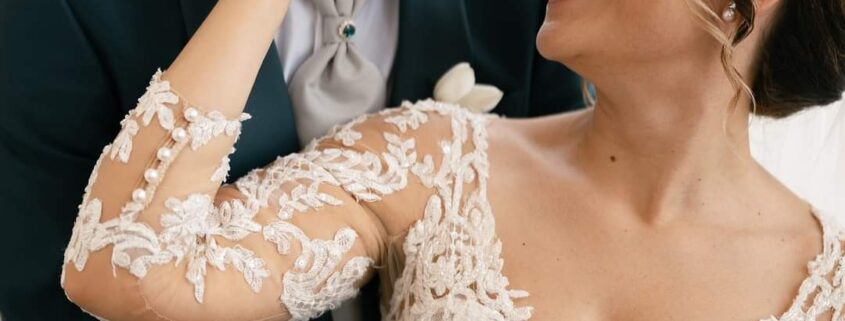 Coppia di sposi sorridenti: lui in abito elegante e lei in abito da sposa raffinato, simbolo di felicità e amore