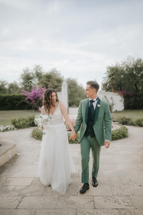 Coppia di sposi felici che si tengono per mano, sorridendo e celebrando il loro amore.