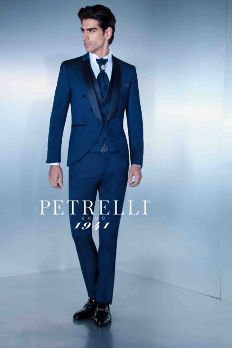 Un completo da uomo elegante blu petrolio, con un cravattone arricchito da spilla gioiello.