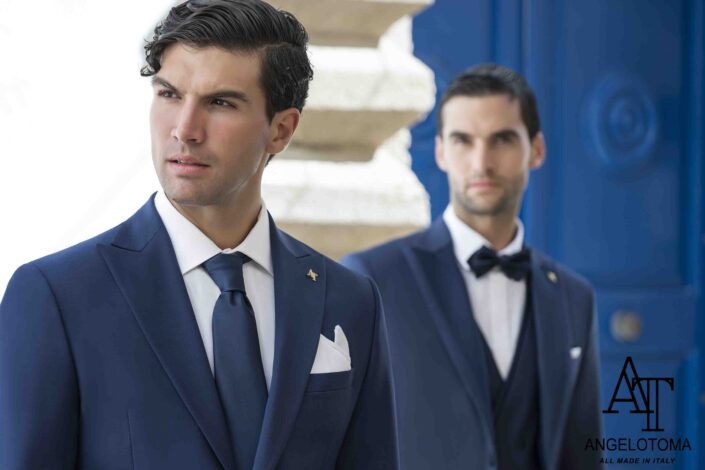 Due uomini in abiti eleganti blu per cerimonia, con sfondo mediterraneo – Moda uomo cerimonia Viterbo.